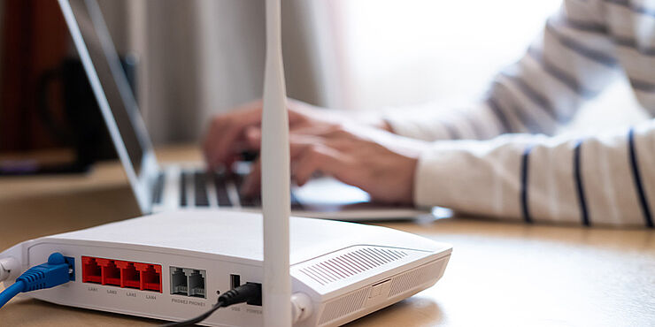 Router und Mann am Laptop im Hintergrund
